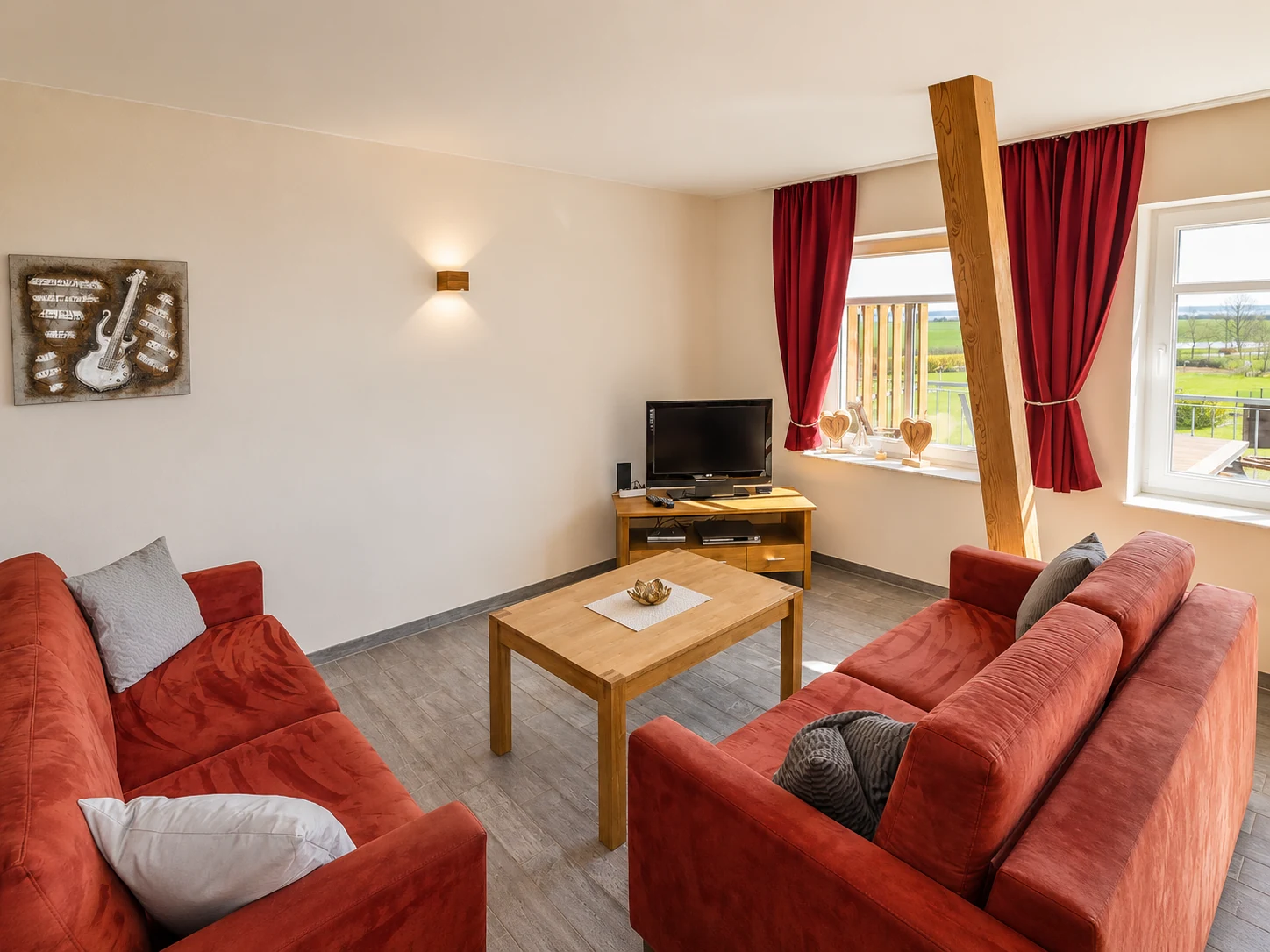 Heller Wohnbereich im Domizil 7 mit Sofa, Holzmöbeln und Blick ins Grüne